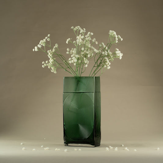 Green vase with baby's breath flowers on a beige background