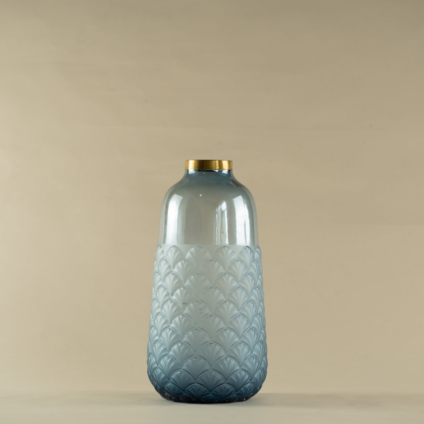 Decorative glass bottle with textured design and gold cap on a beige background