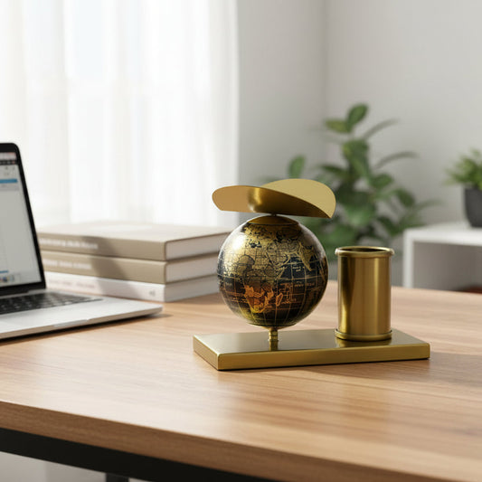 Decorative item with a gold globe and holder on a white surface.