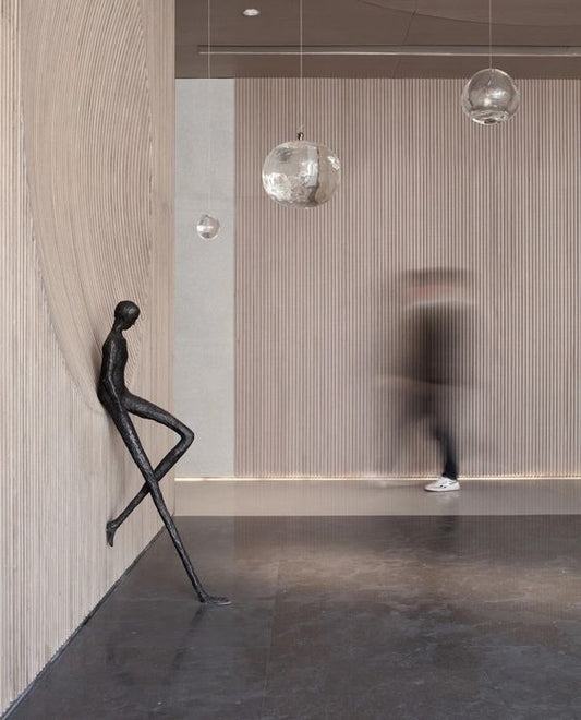 Modern interior with a sculpture of a dancing figure and hanging lights.