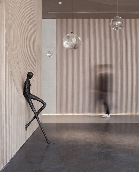 Modern interior with a sculpture of a dancing figure and hanging lights.