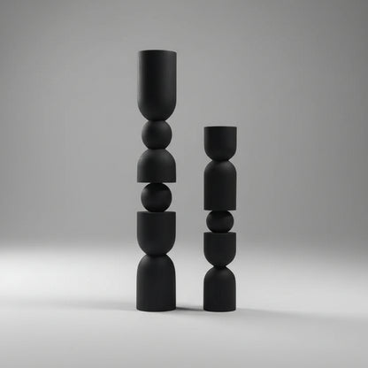 Two black abstract sculptures on a white shelf against a gray wall.