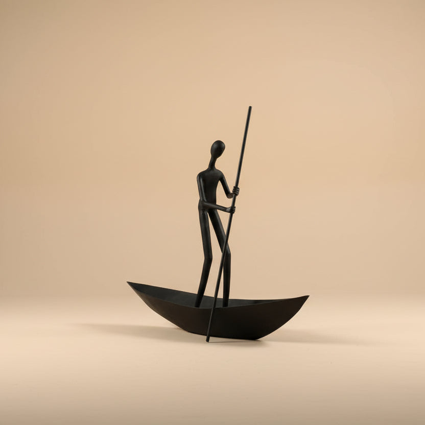 Bronze sculpture of a figure in a boat on a beige background