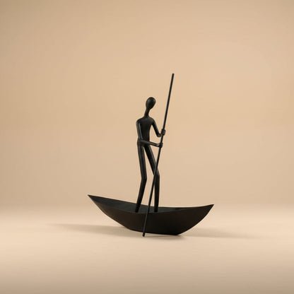 Bronze sculpture of a figure in a boat on a beige background